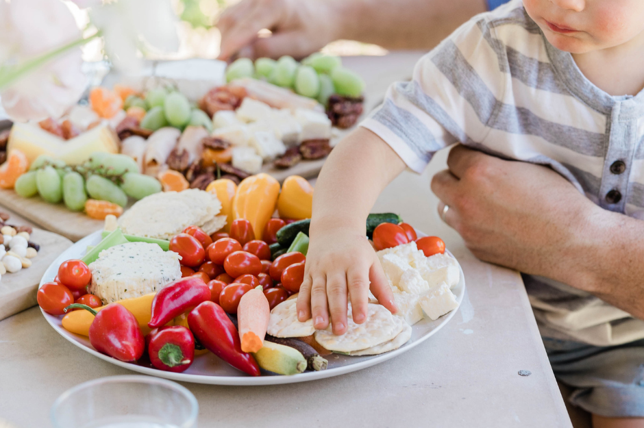 boy reaching for plate of fruit and vegatables